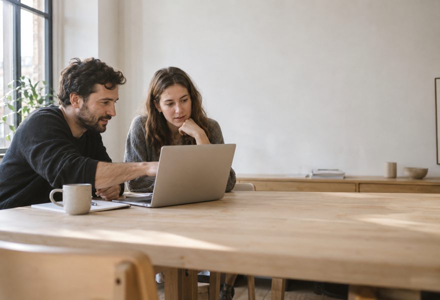 Duas pessoas trabalhando juntas em frente a um notebook